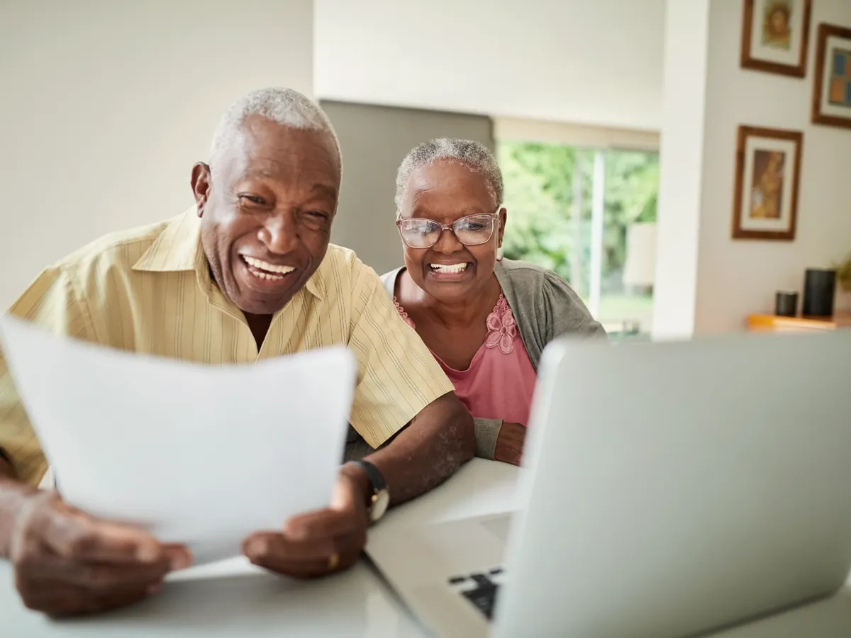 Casal de idosos sorrindo enquanto lê um documento